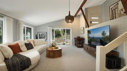 a living room with a white couch and a tv at Arcadia Cottage in Bowral