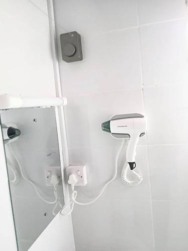 a white bathroom with a hair dryer on the wall at Marine waters retreat Block A in Embu