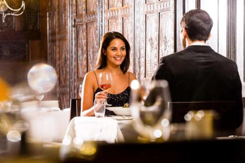 a woman sitting at a table with a glass of wine at Trenython Manor Resort in Fowey