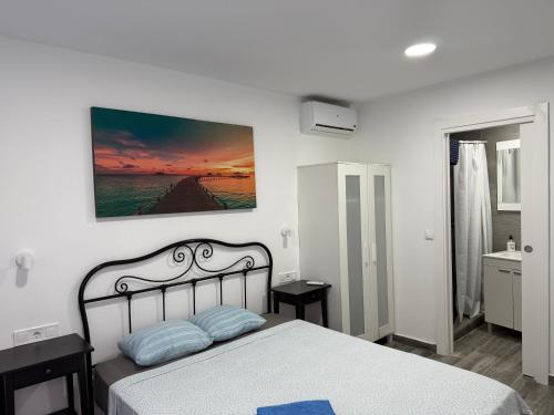 a white bedroom with a bed and a painting on the wall at Rooms Burjassot in Burjassot
