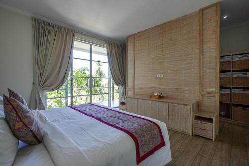 a bedroom with a large bed and a window at Kimana Villa in Manggis