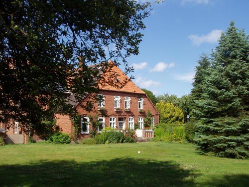 a large brick house with a tree in front of it at Gut Kattenhöhlen in Scharbeutz