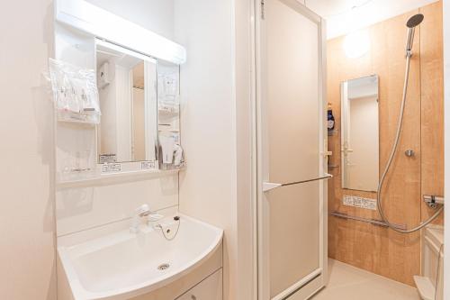 ein weißes Badezimmer mit Waschbecken und Kühlschrank in der Unterkunft Mi-Hotel Ikebukuro 池袋 in Tokio
