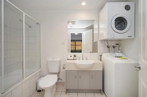 a white bathroom with a toilet and a sink at Quest Warrnambool in Warrnambool