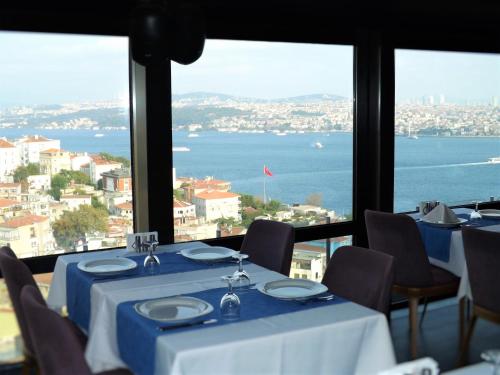 ein Restaurant mit Tischen und Stühlen und Blick auf das Wasser in der Unterkunft Cihangir Hotel in Istanbul