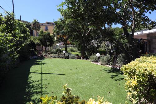 a yard with green grass and trees and bushes at Ambrosio Relais in Sorrento