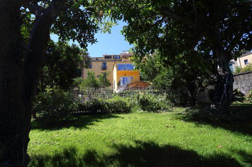 a green yard with a yellow house in the background at Ambrosio Relais in Sorrento
