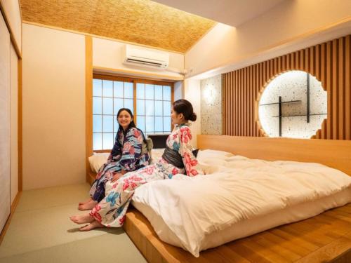 two women sitting on a bed in a room at Hibikino in Shibukawa