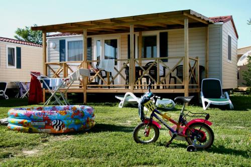 a bike parked in the grass in front of a house at Villaggio Camping Adria in Casal Borsetti