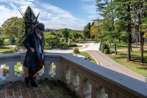 a man standing on a bridge looking over a fence at Castello Di Spessa - Residenze d'epoca in Capriva del Friuli