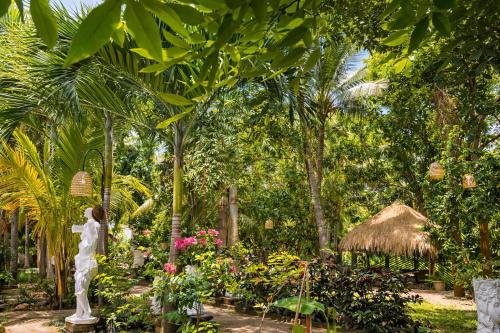 a garden with a statue and flowers and palm trees at Sundaras Infinity Jungle Resort & Spa in Dambulla