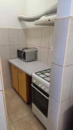 a small kitchen with a stove and a microwave at Monaco Summerland Apartments in Mamaia