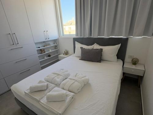 a bedroom with a white bed with towels on it at דירה בוטיק in Rishon LeẔiyyon