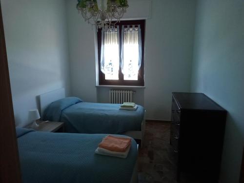 a room with two beds and a dresser and a window at Alloggio per 4 persone con due camere da letto e cucina in Carrù