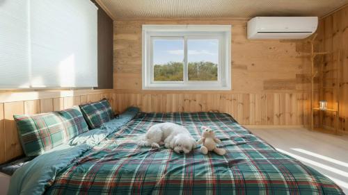 a dog laying on a bed with a teddy bear at Chaesonghwa Glamping in Yeongcheon in Yeongcheon