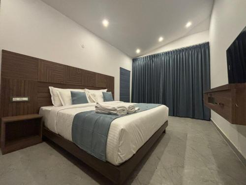 a bedroom with a large bed with a wooden headboard at Kodai Square Homestay in Kodaikānāl