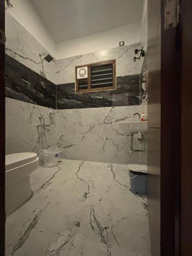 a marble bathroom with a toilet and a sink at Kodai Square Homestay in Kodaikānāl