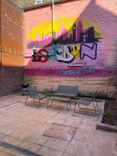 a mural on a wall with benches in front at Chamberlayne Inn in London