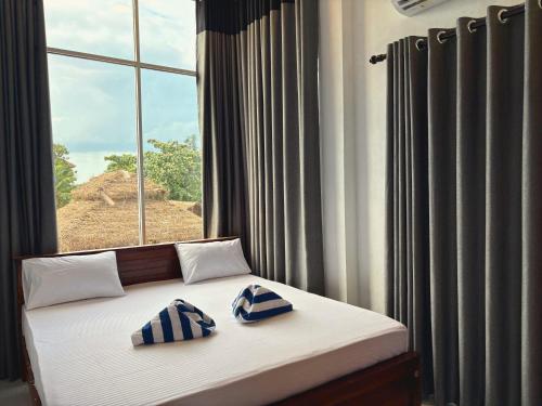 a bed with two blue and white pillows in front of a window at The Amora in Arugam Bay