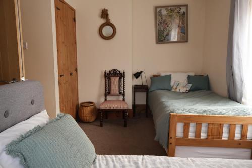 a bedroom with two twin beds and a chair at Lighthouse cottage in Watchet