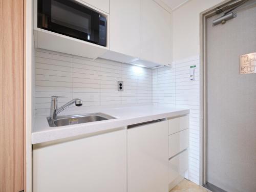 a white kitchen with a sink and a microwave at Uljiro Coop Residence Dongdaemun in Seoul