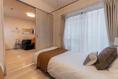 ein Schlafzimmer mit einem Bett und einem großen Fenster in der Unterkunft Mi-Hotel Ikebukuro 池袋 in Tokio