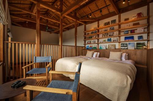 a bedroom with two beds and a chair in it at TheMana Village in Tosashimizu