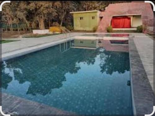 a swimming pool with blue water in a yard at Green valley resort kanha in Kānha