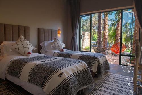 due letti in una stanza con una grande finestra di Le Bled Ferme a Marrakech