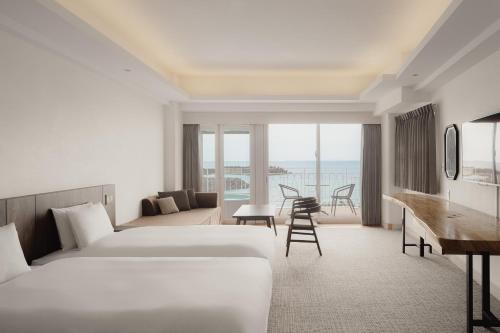 a hotel room with two beds and a desk at Anse Yomitan Toya in Yomitan