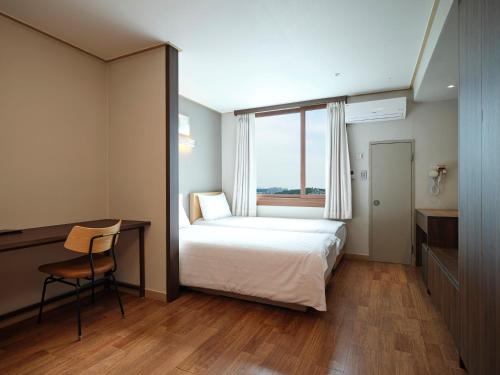a bedroom with a bed and a desk and a window at Western Coop Hotel & Residence Dongdaemun in Seoul