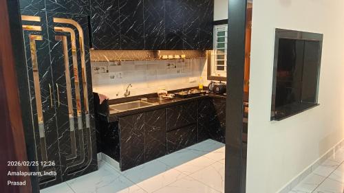 a kitchen with black marble counters and a sink at Suneetha Presidency in Amalāpuram