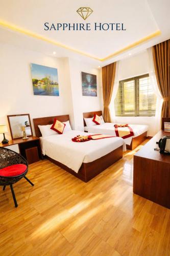 a hotel room with two beds and a table at Sapphire HOTEL HUE in Hue