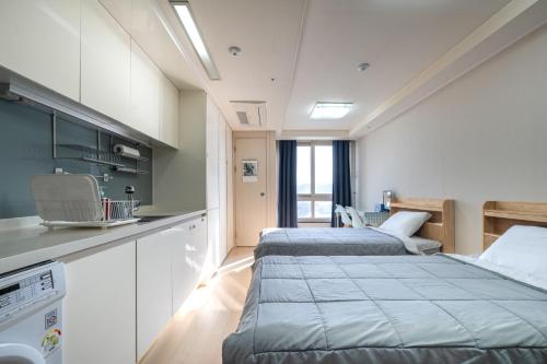 two beds in a room with a kitchen at 김천 포유스테이 in Oksan