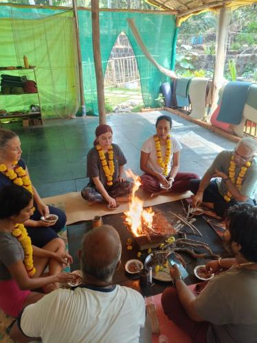 a group of people sitting around a fire in a tent at Bhakti Yoga Ashram in Canacona