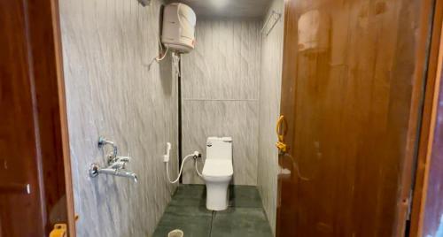 a bathroom with a toilet and a phone on the wall at The Wildcamp - Coorg in Kushālnagar