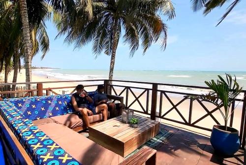 two people sitting on a couch in front of the beach at Private Beachfront Home-Ocean View-Total Privacy in Ampeni