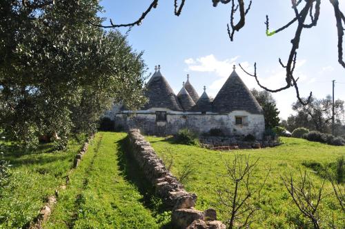 an old house in a field with a stone wall at Trulli La Gufa in Ostuni