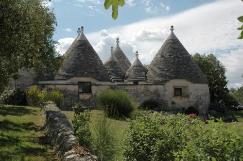 an old stone building with pointed roofs in a garden at Trulli La Gufa in Ostuni