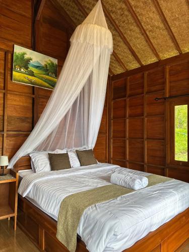 a bedroom with a bed with a mosquito net at Kubu Waru Bali in Munduk