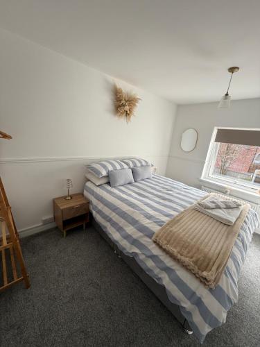 a bedroom with a blue and white bed with a window at Silver stays, calm coastal stay , close to beach in Gorleston-on-Sea