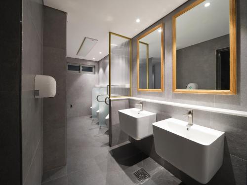 a bathroom with three sinks and two mirrors at Western Coop Hotel & Residence Dongdaemun in Seoul