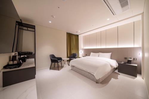 a hotel room with a bed and a desk and chairs at The Gleam Hotel in Incheon