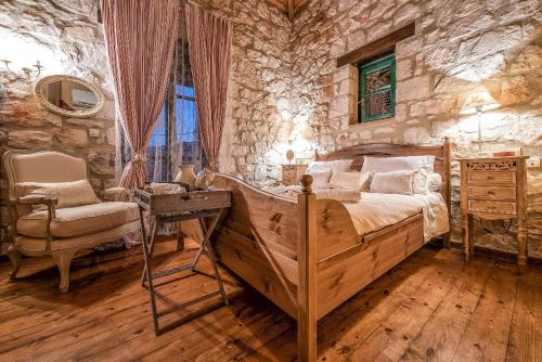a bedroom with a bed and a stone wall at Anassa Villa in Mouzákion