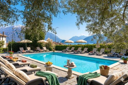 ein Pool mit Liegestühlen und ein Resort mit Bergen im Hintergrund in der Unterkunft Hotel Royal in Menaggio