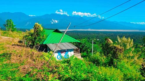 a small house with a green roof on a hill at Nature's Harmony Heaven in Dāmbuk