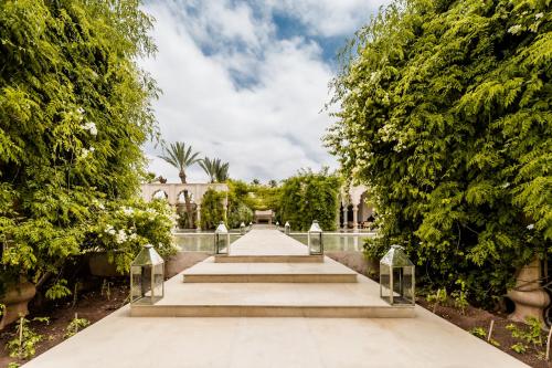 a walkway through a garden with trees and a building at Palais Namaskar in Marrakech