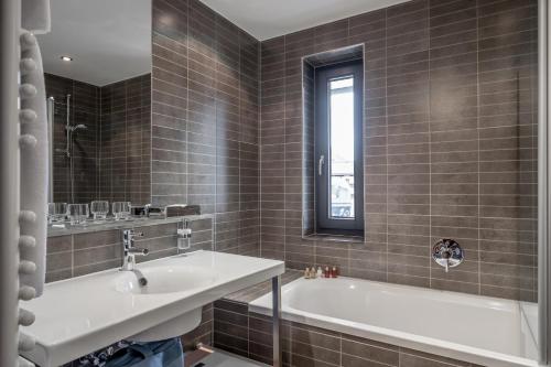 a bathroom with a tub and a sink and a window at Josl Mountain Lounging Hotel - Adults only! in Obergurgl