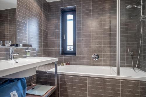 a bathroom with a tub and a sink and a window at Josl Mountain Lounging Hotel - Adults only! in Obergurgl