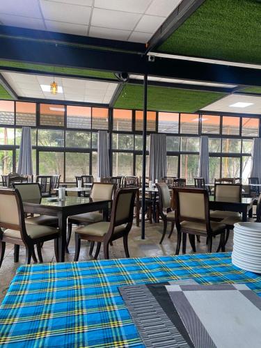 a dining room with tables and chairs and windows at Lake Naivasha Lazarus Lodge in Naivasha